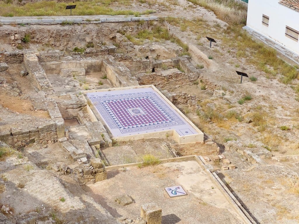 Ancient Roman Therms, beige ruins and checkered, multi-colored mosaic in the center.