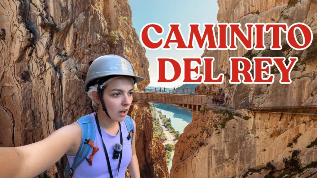 A person wearing a helmet and backpack stands on a narrow walkway along a steep rocky gorge. The words "Caminito del Rey" appear in large red letters. A river and more cliffs are visible in the background.