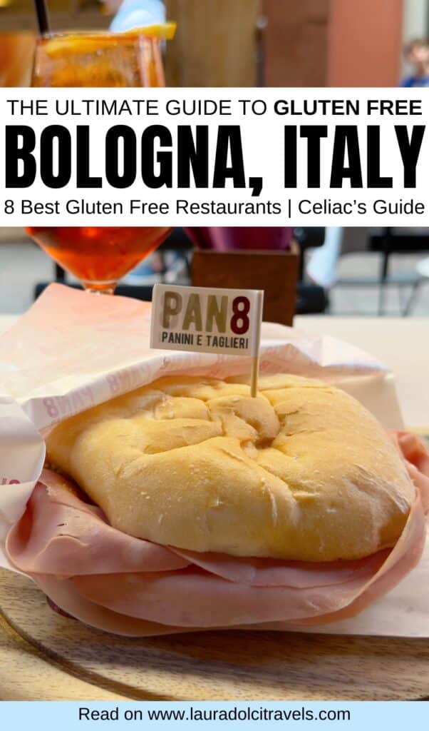 A large gluten-free sandwich with ham on a bun, topped with a small “PAN8” flag, sits on a wooden table with a drink in the background. Overlaid text promotes a gluten-free guide to Bologna, Italy.