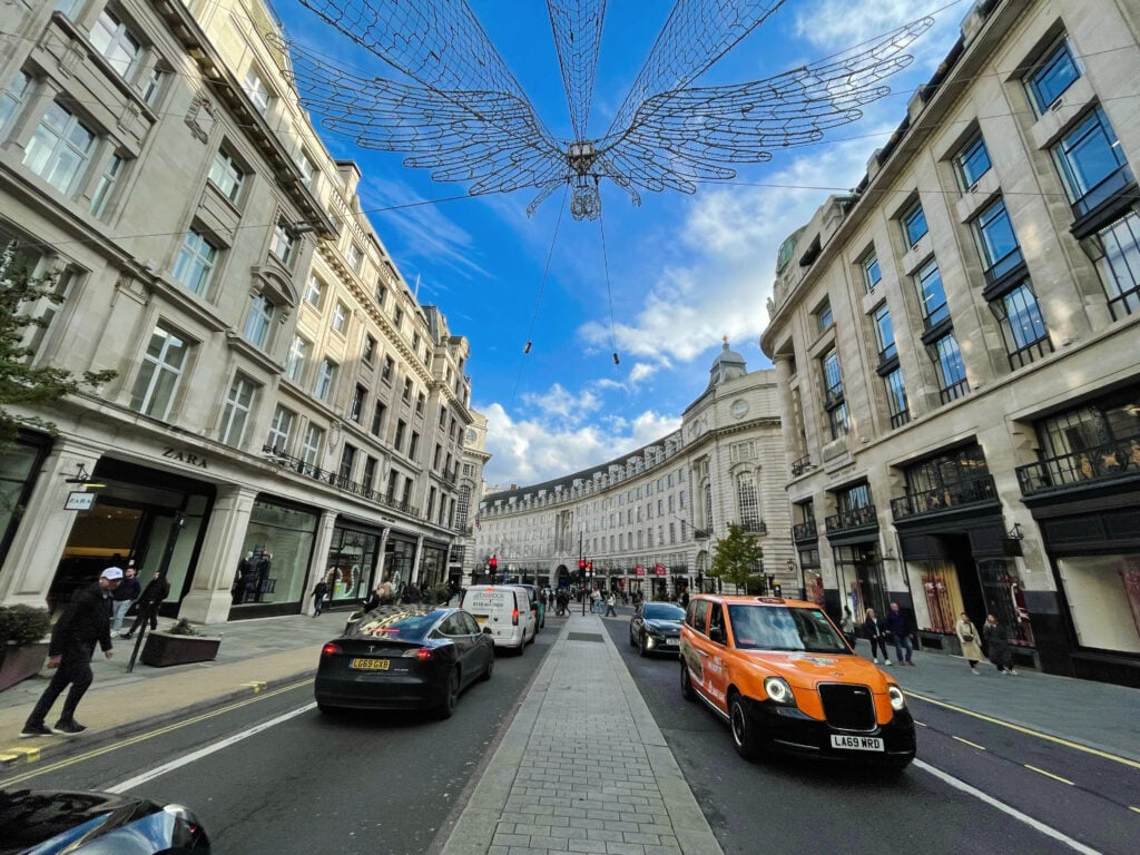 Regent street, one of London's most famous streets, with cars and buildings. The hanging lights captures the unique atmosphere of London in November.
