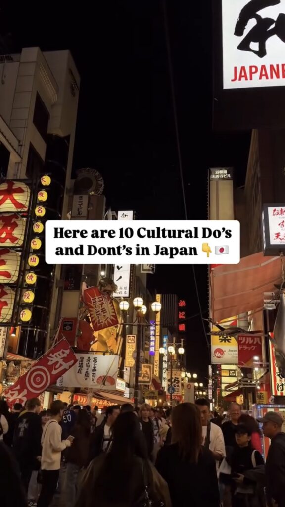 A busy street in Japan at night, filled with people and bright neon signs. Text overlay reads, “Here are 10 Cultural Do’s and Don’ts in Japan” with a down arrow and Japanese flag emoji.
