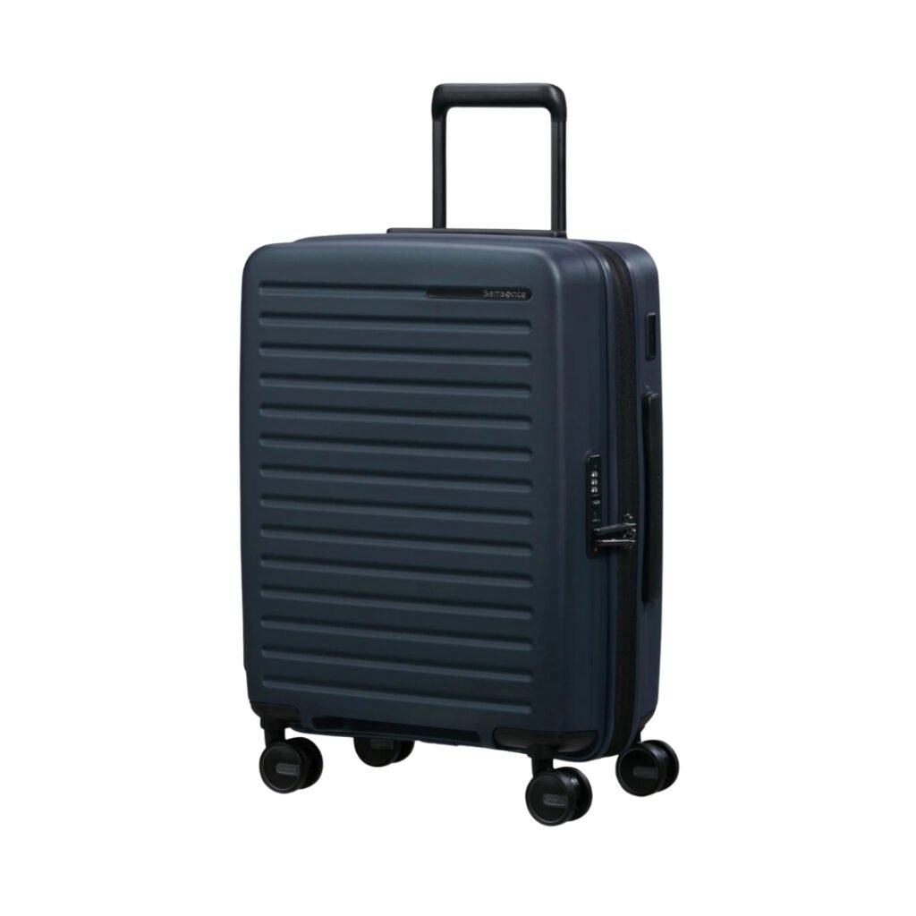A dark blue hard-shell suitcase with horizontal grooves, four swivel wheels, a telescoping handle, and a built-in side lock, standing upright on a white background.