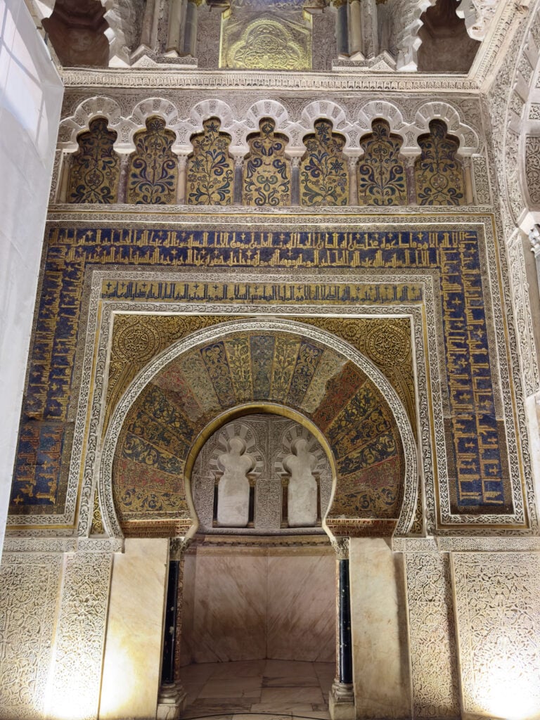 Intricately decorated arches and mosaic tilework in a Moorish architectural interior.